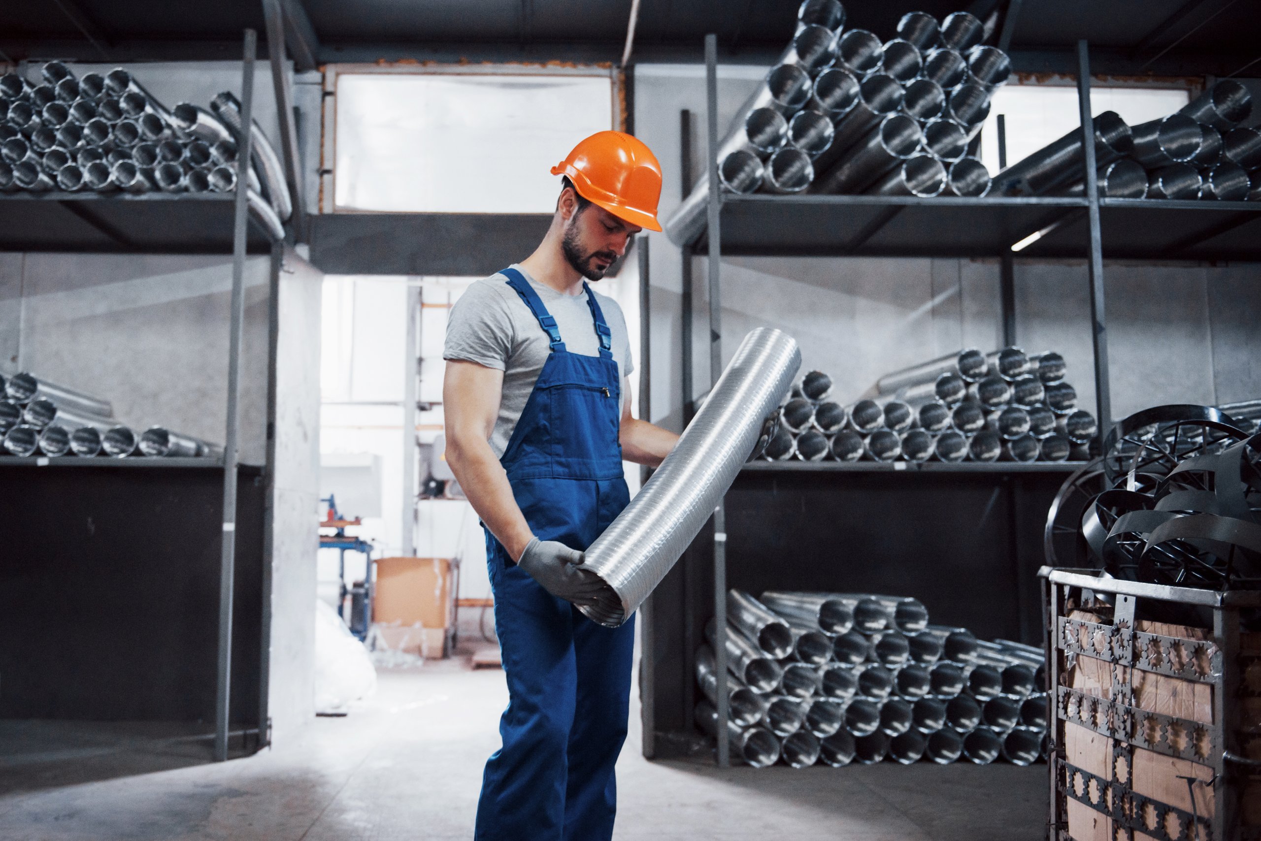 Ouvrier dans un atelier métallurgique chauffé, bâtiment industriel éligible aux primes CEE